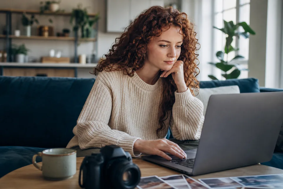 Woman choosing photos on a laptop in a bright apartment