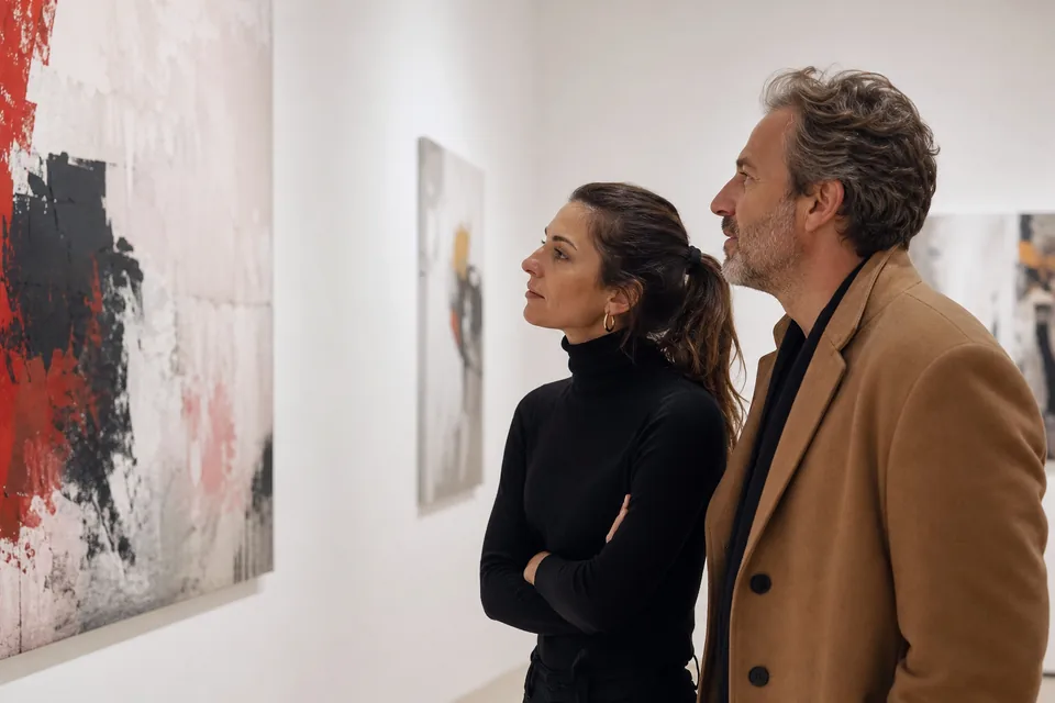Couple looking at abstract paintings in a modern art gallery